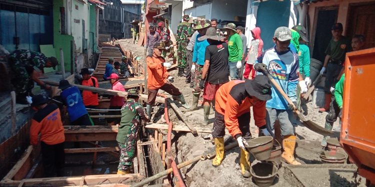 Terik Sinar Matahari Tak Surutkan Satgas TMMD, Ormas dan Warga Dalam Pengecoran Begesteng Kanan Kiri Saluran Air